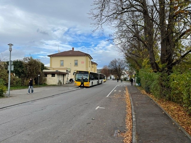 Bahnhofstratße mit Bahnhofsgebäude und Bus im HIntergrund